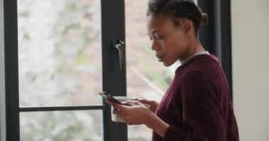 Pencerenin yanında cep telefonu kullanan genç Afrikalı Kadın