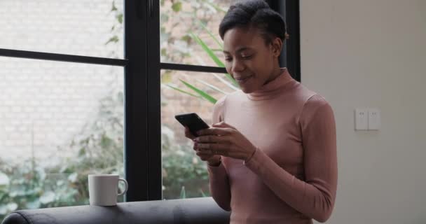 Glad afrikansk kvinna använder mobil hemma — Stockvideo