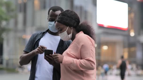 Schwarzes junges Paar trägt Maske und redet auf der Straße — Stockvideo