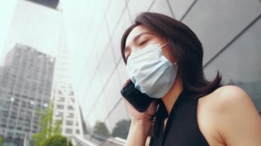 Maskeli kadın cep telefonuyla konuşuyor.