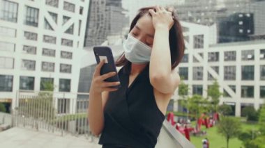 Maskeli bir kadın cep telefonuyla görüntülü sohbet ediyor.