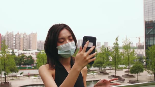 Maskeli bir kadın cep telefonuyla görüntülü sohbet ediyor. — Stok video
