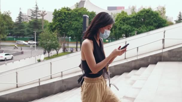 Женщина в маске с помощью мобильного телефона в городе — стоковое видео