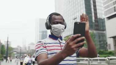 Sokakta maskeli bir zenci telefonla konuşuyor.