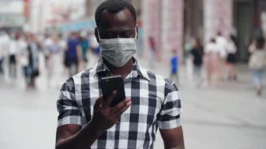 Sokakta maskeli bir zenci telefonla konuşuyor.