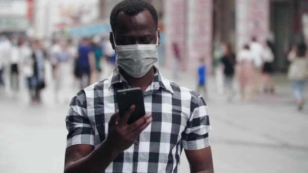 Orang kulit hitam berbicara di telepon di jalan dengan topeng — Stok Video