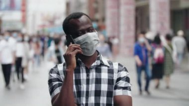 Sokakta maskeli bir zenci telefonla konuşuyor.