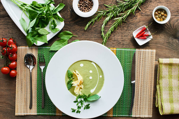 Soup with zucchini in white plate on wooden table