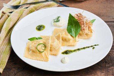 Beyaz tabakta yemek ravioli ördek ve krema sos ile