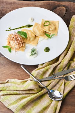 Beyaz tabakta yemek ravioli ördek ve krema sos ile