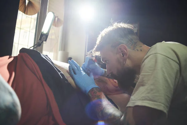 Cliente Sdraiato Sul Letto Tatuatore Facendolo Tatuaggio Laboratorio Scuro — Foto Stock