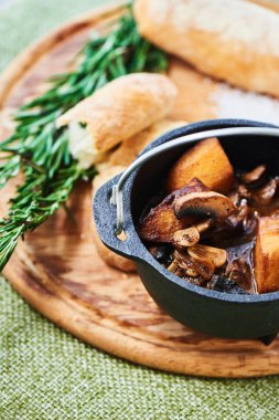 Mantar ve sosu demi glace demir tencere ve ahşap plaket üzerine ekmek ile Dana Yahni 