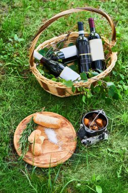 demir tencere ve yeşil çimen, sağlıklı piknik kavramı üzerinde kırmızı şarap şişeleri ile ahşap tahta ve sepet gevrek baget mantarlı dana yahni 