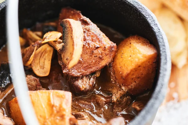 Mantar ve sosu demi glace demir tencere ve ahşap plaket üzerine ekmek ile Dana Yahni 