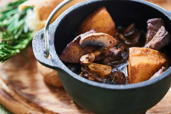 Mantar ve sosu demi glace demir tencere ve ahşap plaket üzerine ekmek ile Dana Yahni 