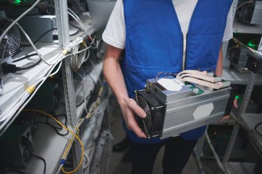 Madencilik. Bir adam bir cryptocurrency çiftlikte çalışıyor. Bitcoin madencilik ekipmanları elinde tutan