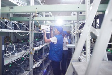 Madencilik. Kripto birimlerinin çıkarılması için bir çiftlikte çalışan bir adam. Bitcoin iş