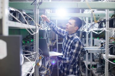 Madencilik. Kripto birimlerinin çıkarılması için bir çiftlikte çalışan bir adam. Bitcoin iş