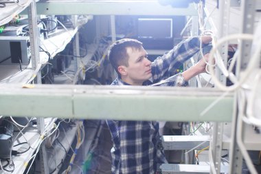 Madencilik. Kripto birimlerinin çıkarılması için bir çiftlikte çalışan adam. Bitcoin iş