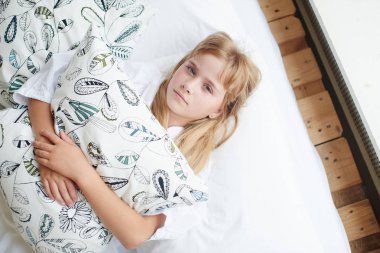 Kameraya bakarak ve beyaz yatakta yatarken yastık sarılma kızın üstten görünüm