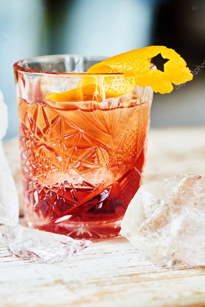 Alcoholic Negroni cocktail consisting of vermouth and liqueur with gin and citrus peel in glass beaker