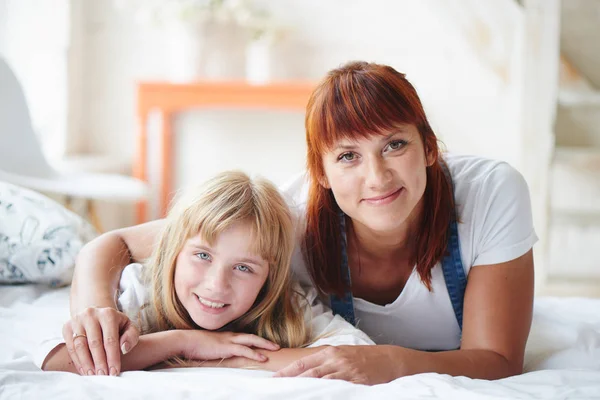 Figlia Felice Con Madre Guardando Macchina Fotografica Mentre Sdraiato Sul — Foto Stock