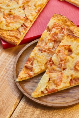 Dilim pizza ananas ve peynir ile pişmiş jambon ile kırmızı yüzeyde olduğunu