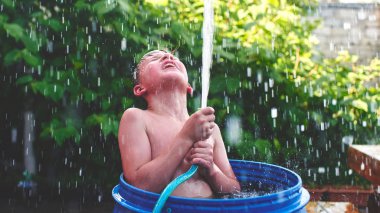 Hortum tutarak ve su duran avlu, mavi varil içinde yukarı yönetmenlik çocuk