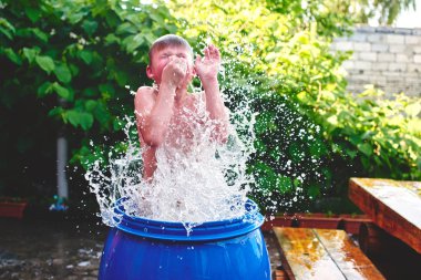 Avlu, mavi varil içinde sıçramasına ile su çıkan çocuk