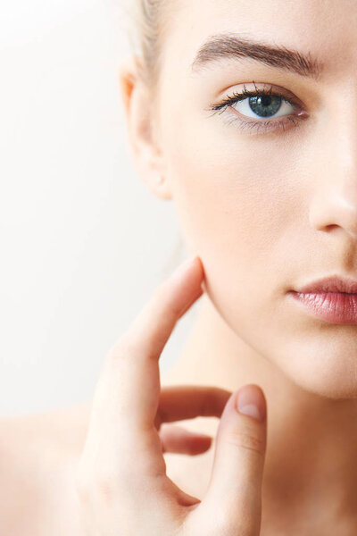 Portrait of girl with make-up touching face closeup on white background