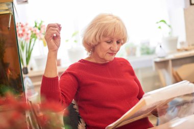 evde otururken kırmızı kazaklı Nakışlı içinde yaşlı kadın 