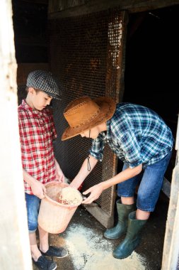 İki kardeş bir tavuk kümesi katında gıda dağılım