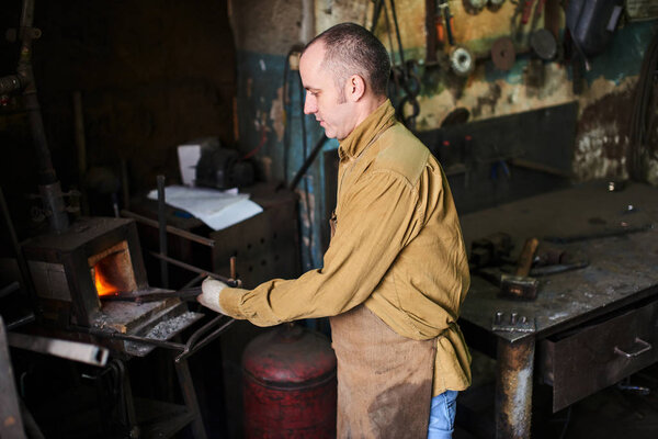 Blacksmith in the production process of metal products handmade in the workshop