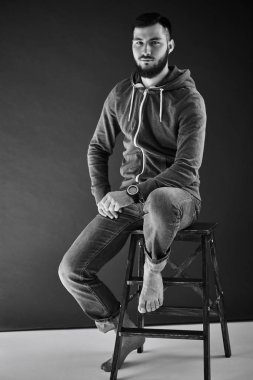tahta sandalyede otururken kameraya bakarak rahat kıyafetler giymiş yakışıklı sakallı adam portresi yakın çekim 
