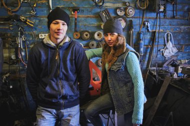 Bisiklet atölyesinde tamir araçlarıyla duvarının yakınında duran arkadaşlar