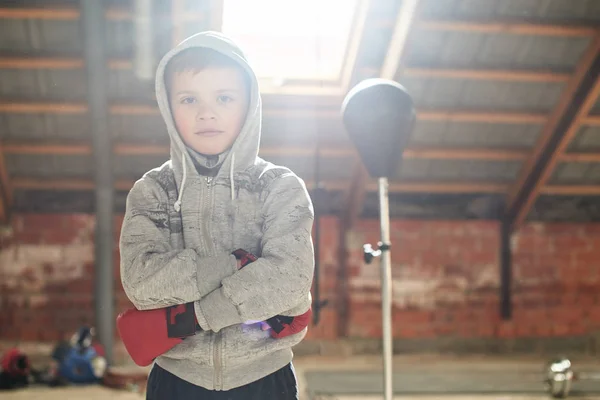 little boy wearing boxing gloves fighting in gym