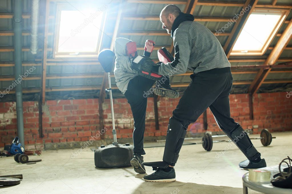 Father in sport suit with son working out boxing blow in makeshift home gym  