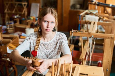 tezgah atölyesinde dokumacı, elinde özel araç ile yakın duran kadın