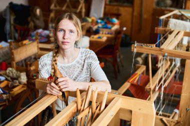 tezgah atölyesinde dokumacı, elinde özel araç ile yakın duran kadın