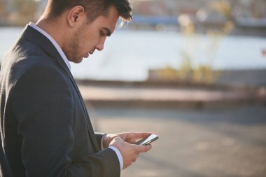 smartphone ekranında açık arıyor takım elbiseli yakışıklı işadamı 