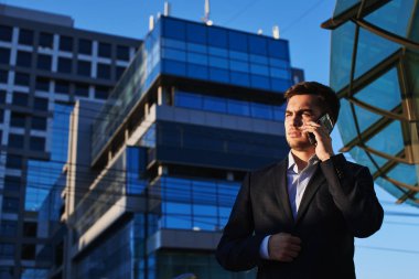 yakışıklı işadamı smartphone duran şehir merkezinde inşa verandada konuşurken 