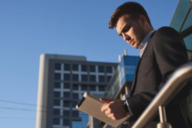 yakışıklı işadamı elbiseli Caddesinde duran tablet PC'yi kullanma 