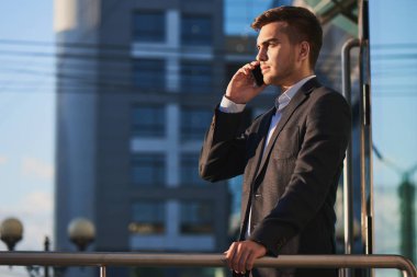 telefon duran iş binanın verandada konuşurken takım elbiseli genç işadamı