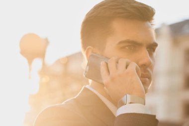 takım ve Smartphone cep telefonu ile şehir merkezinde güneşli gün konuşmak smartwatch işadamı 