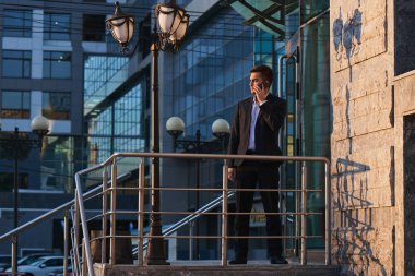 telefon duran iş binanın verandada konuşurken takım elbiseli genç işadamı