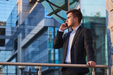 telefon duran iş binanın verandada konuşurken takım elbiseli genç işadamı