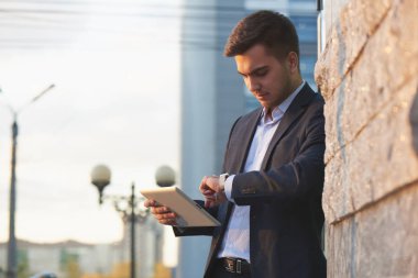 takım elbiseli yakışıklı işadamı tablet pc tutarak ve açık duran süre bakarak 
