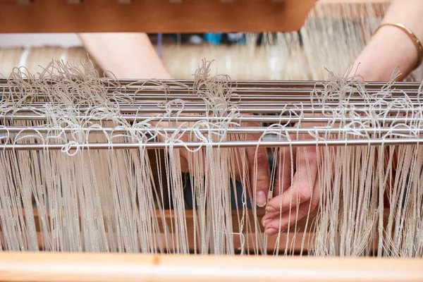 female hands in production process of textiles handmade on loom, close-up