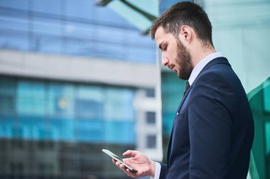 smartphone açık, yakın çekim kullanarak takım elbiseli sakallı işadamı 