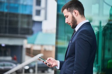 smartphone açık, yakın çekim kullanarak takım elbiseli sakallı işadamı 